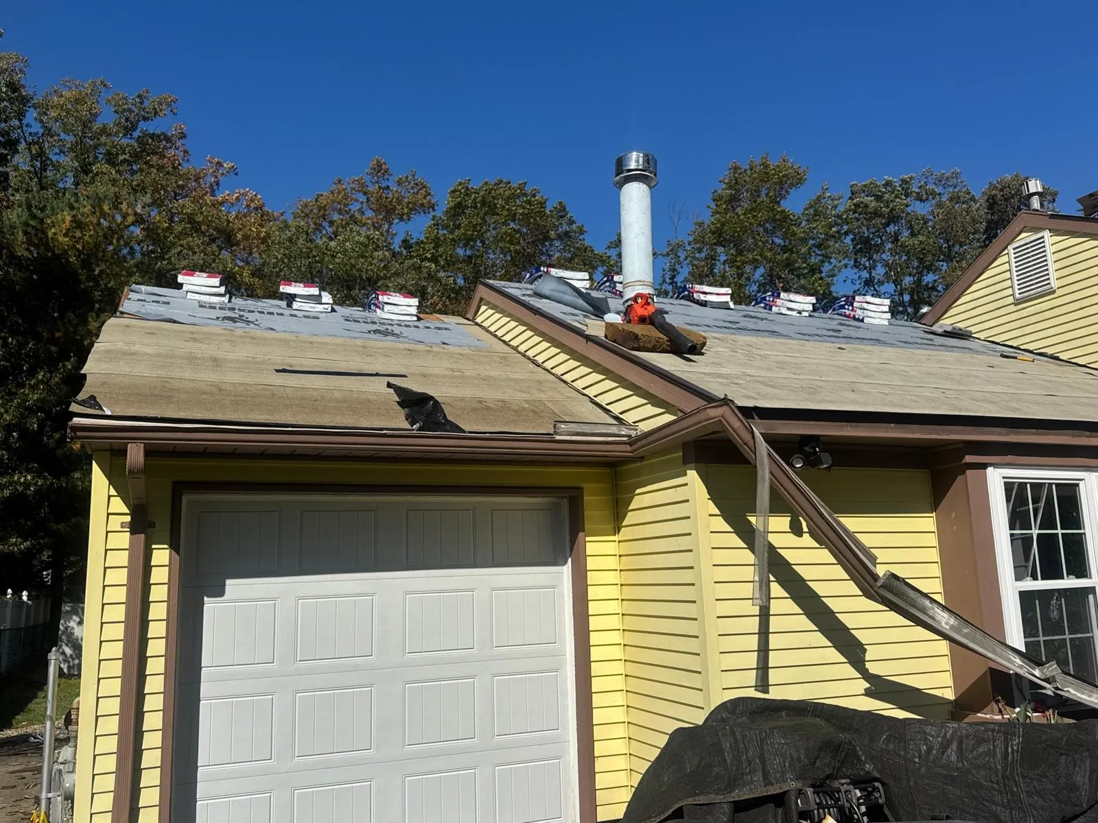 Yellow house with a roof being repaired after storm damage